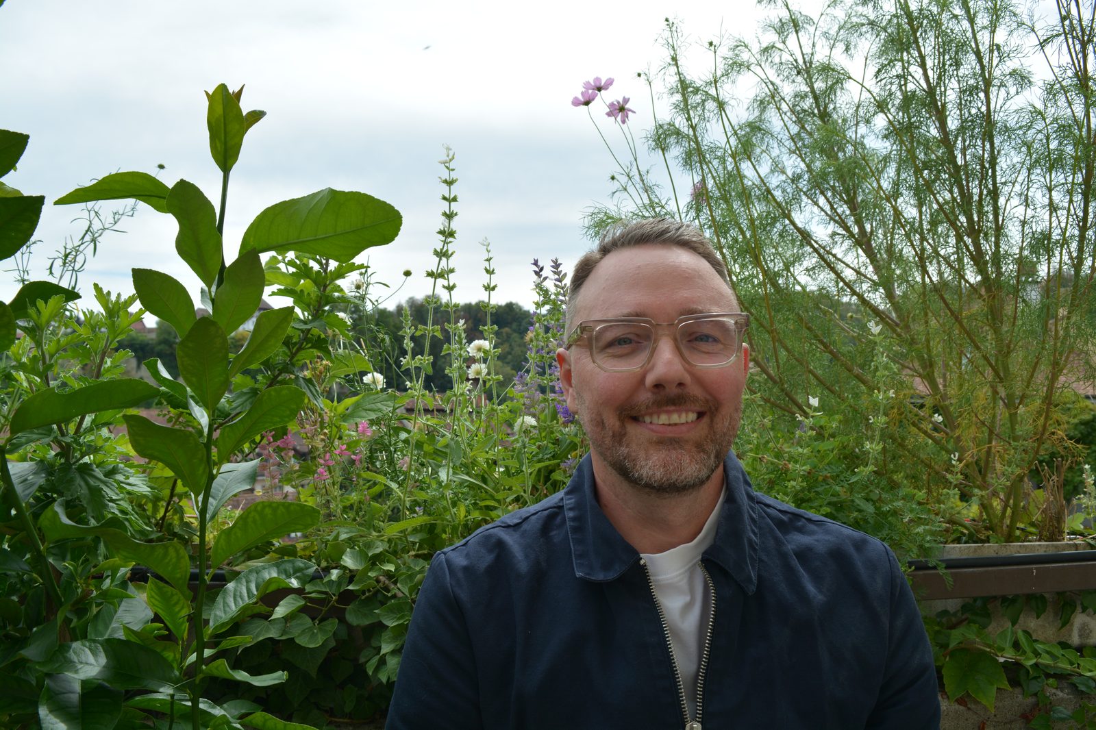 David Ruffieux souriant au milieu de fleurs sauvages, sous un ciel dégagé